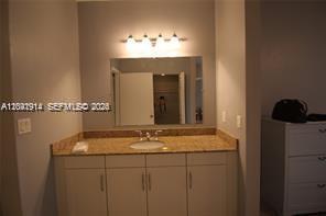 A bathroom vanity with a granite countertop, sink, mirror, and overhead lighting — 7280 SW 90th St # 506, Miami FL 33156, MIAMI, FL