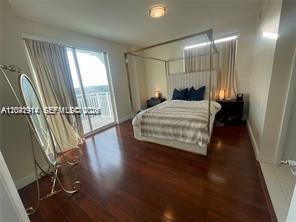 A bedroom features a canopy bed, hardwood floors, and a sliding glass door to a balcony — 7280 SW 90th St # 506, Miami FL 33156, MIAMI, FL