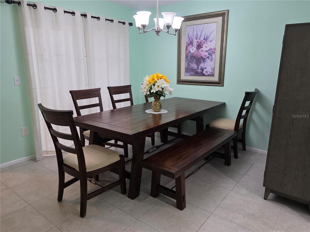 A dining room features a dark wood table with chairs and a bench on tile flooring — 3607 AVENIDA MADERA UNIT B, BRADENTON, FL