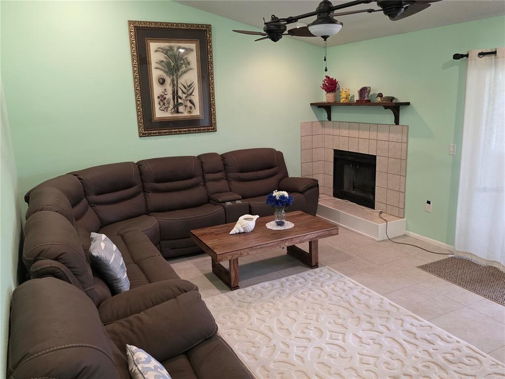 A living room features a large brown sectional sofa, a coffee table, and a fireplace — 3607 AVENIDA MADERA UNIT B, BRADENTON, FL
