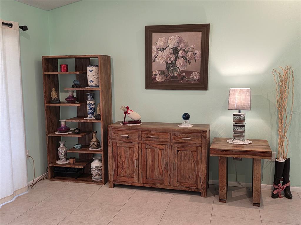 A room features a wooden bookshelf, a matching sideboard, and a side table with a lamp — 3607 AVENIDA MADERA UNIT B, BRADENTON, FL