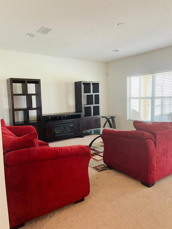 A living room features two red sofas, a dark wood entertainment center, and a glass table — 3603 LIGHT PORT WAY, KISSIMMEE, FL
