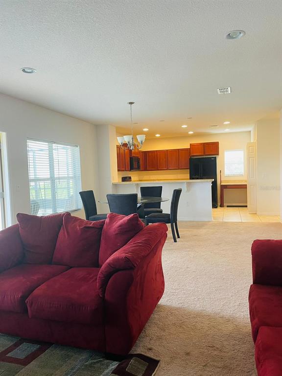 A carpeted living room opens to a dining area and kitchen with wood cabinets — 3603 LIGHT PORT WAY, KISSIMMEE, FL