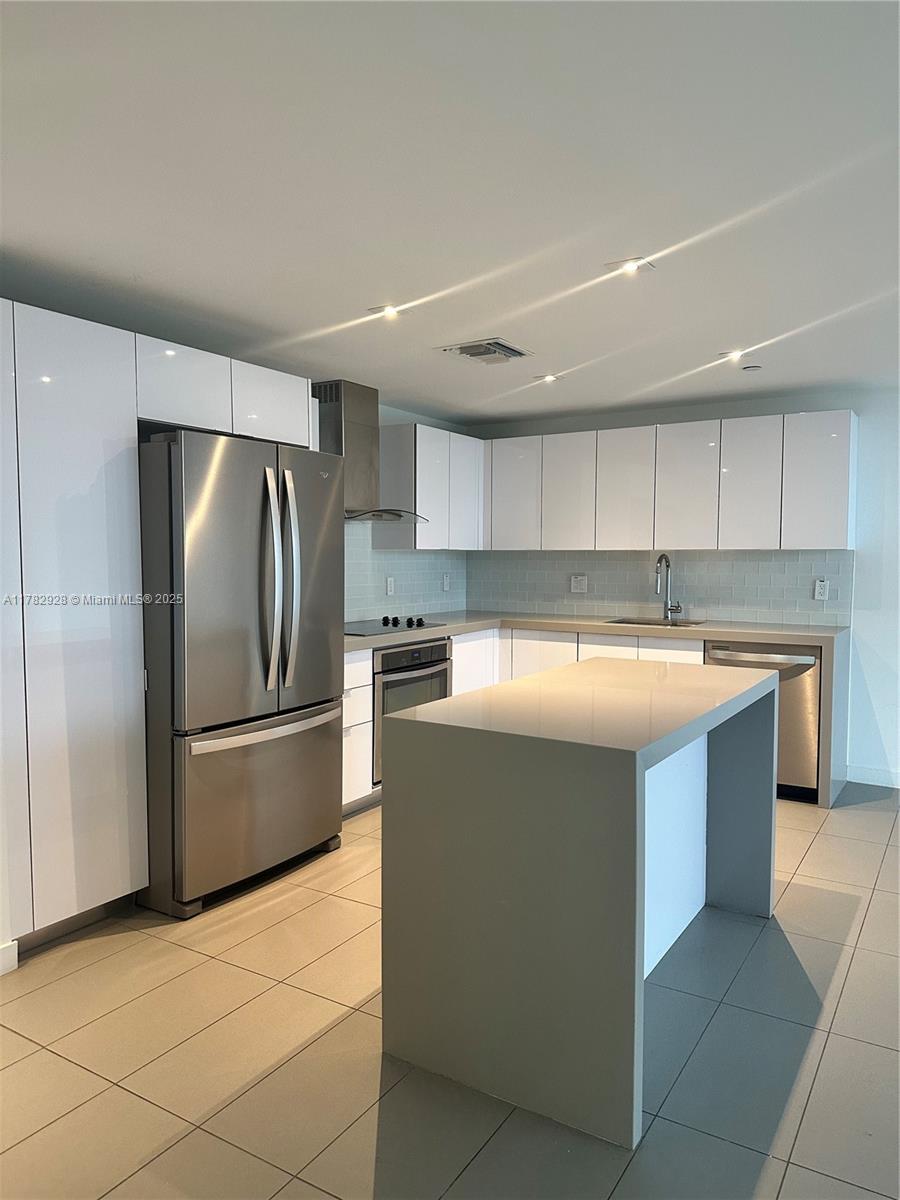 A modern kitchen features white cabinets, stainless steel appliances, and a gray stone island — 1600 NE 1st Ave # 2017, Miami FL 33132, MIAMI, FL