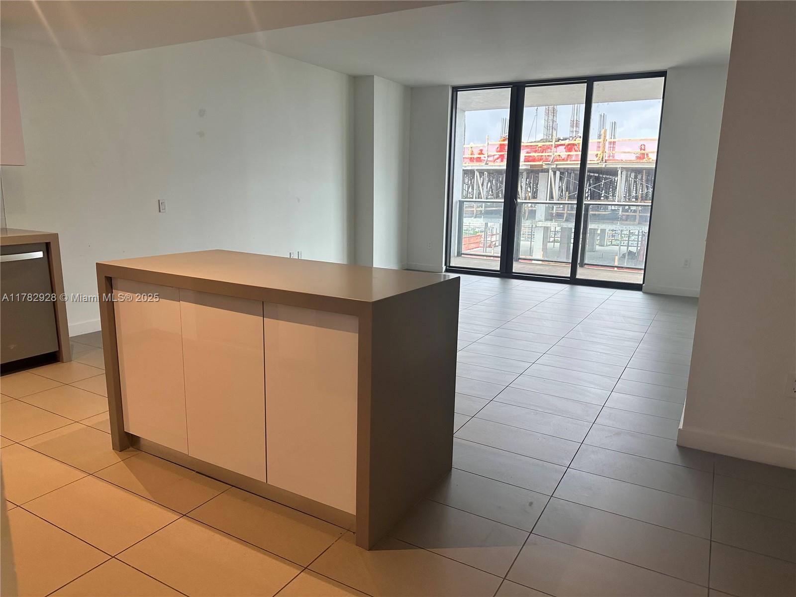 A modern kitchen island with white cabinets sits in an open room with tiled floors — 1600 NE 1st Ave # 2017, Miami FL 33132, MIAMI, FL