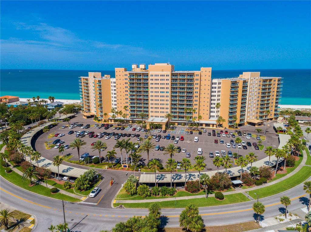An aerial view shows a large beachfront apartment complex with a circular parking lot — 880 MANDALAY AVENUE UNIT N412, CLEARWATER, FL