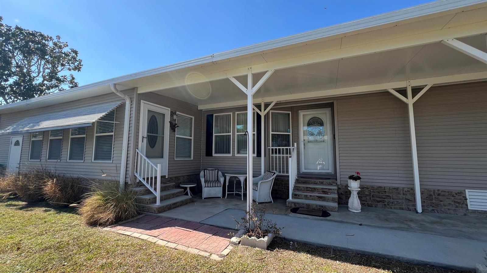 The exterior of a manufactured home features a covered patio, two entry doors, and siding — 621 Puffin Drive, Barefoot Bay FL 32976, BAREFOOT BAY, FL