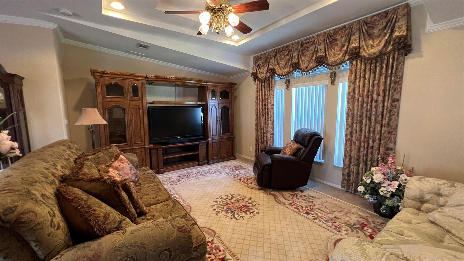 A living room features a large wooden entertainment center, patterned furniture, and heavy window drapery — 621 Puffin Drive, Barefoot Bay FL 32976, BAREFOOT BAY, FL