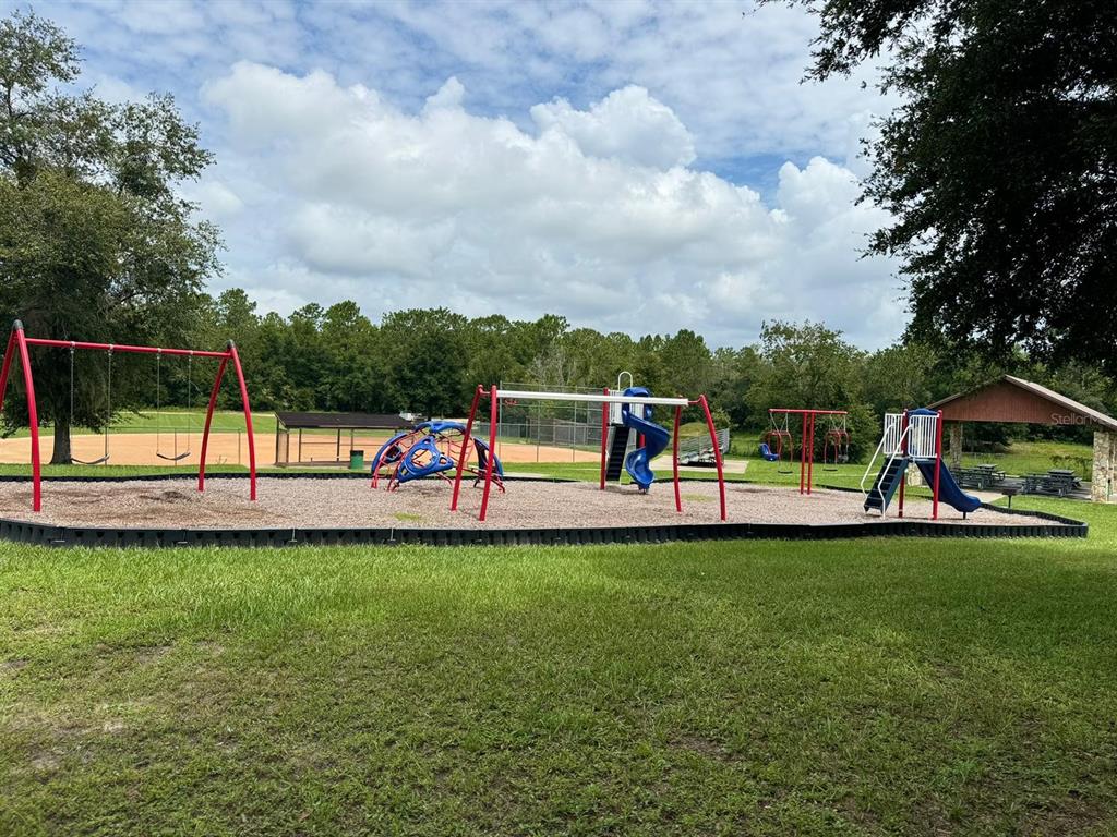 A playground with swings, a climbing structure, and slides sits on a wood-chipped surface — 6783 N PAVILION LOOP, CITRUS SPRINGS, FL