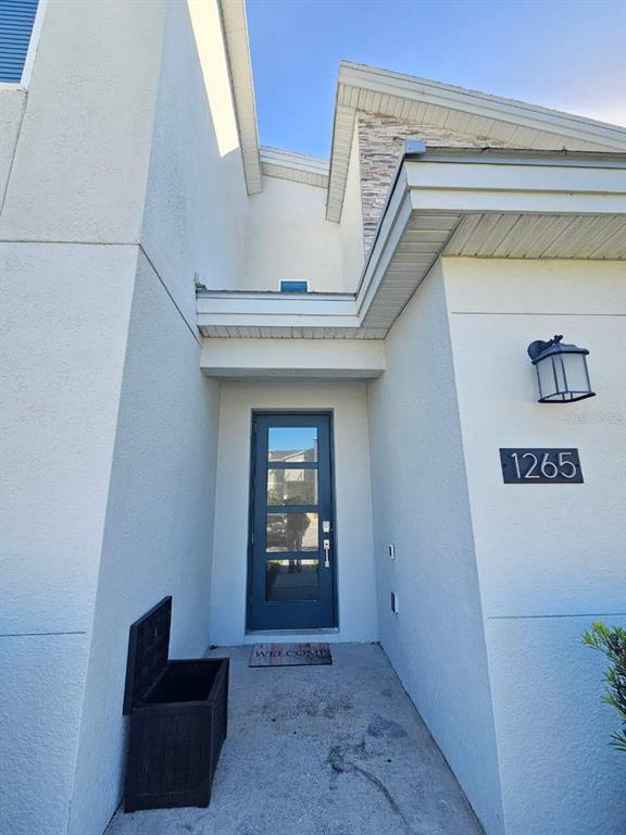 The exterior entrance features a blue glass-paneled door, a wall-mounted lantern, and a storage bin — 1265 CHALLENGE DRIVE, DAVENPORT, FL