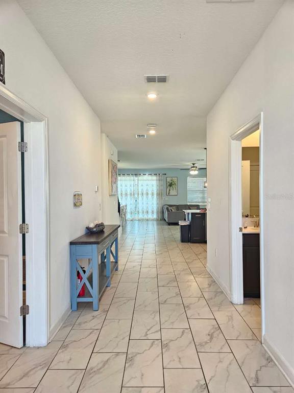 A hallway with marble-look tile flooring leads to an open-concept living area and kitchen — 1265 CHALLENGE DRIVE, DAVENPORT, FL