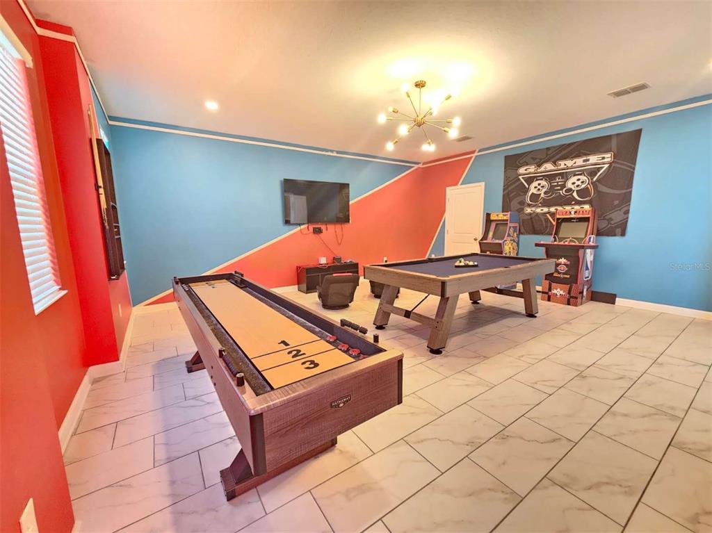 A game room features a shuffleboard table, a pool table, arcade cabinets, and tile flooring — 1265 CHALLENGE DRIVE, DAVENPORT, FL