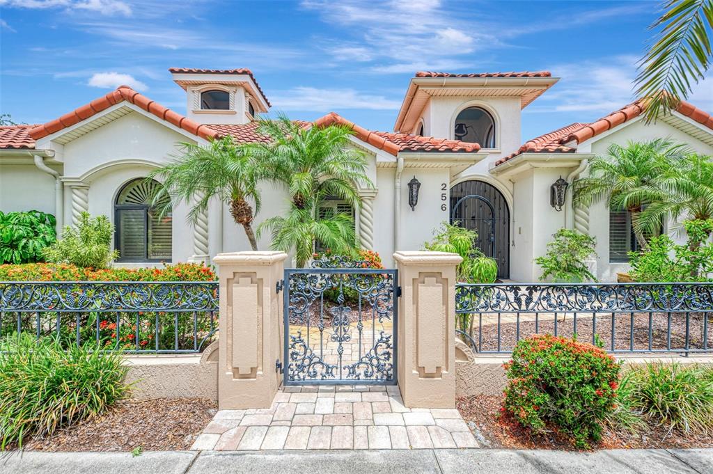 A screened-in patio features a curved swimming pool, stone decking, and red-striped curtains — 256 PENSACOLA ROAD, VENICE, FL