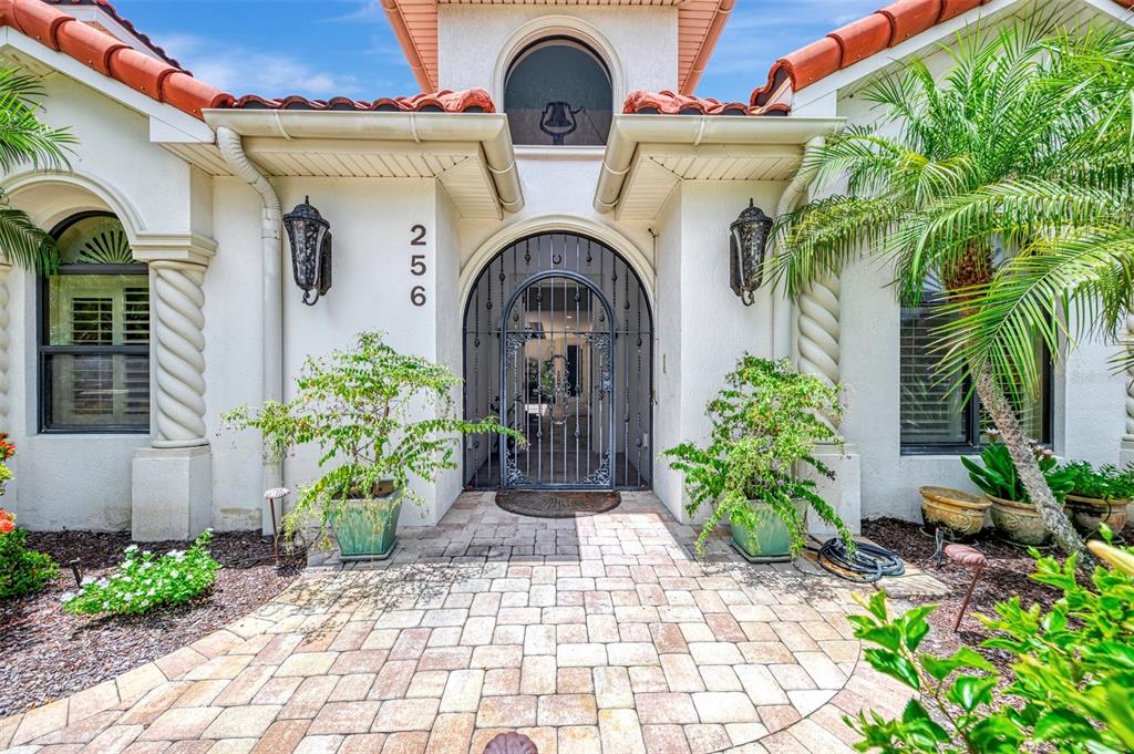 The exterior of a single-story stucco home features a tiled roof and a gated courtyard — 256 PENSACOLA ROAD, VENICE, FL