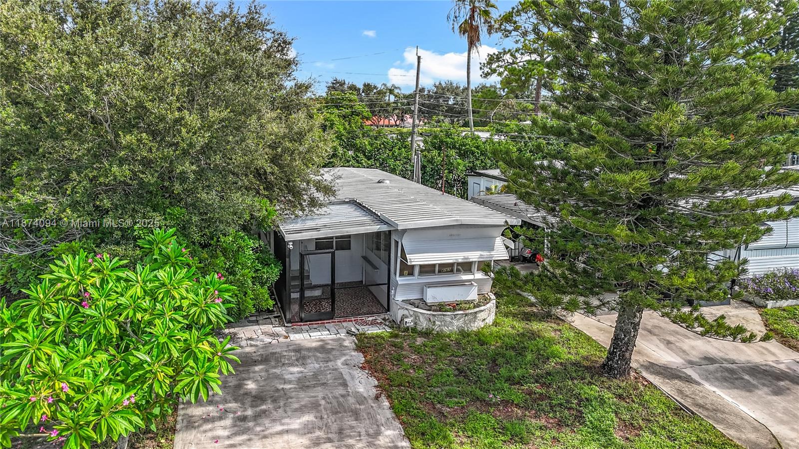 An exterior view of a single-story mobile home with a screened porch and metal roof — 4165 S 88th Ct S, Boynton Beach FL 33436, BOYNTON BEACH, FL