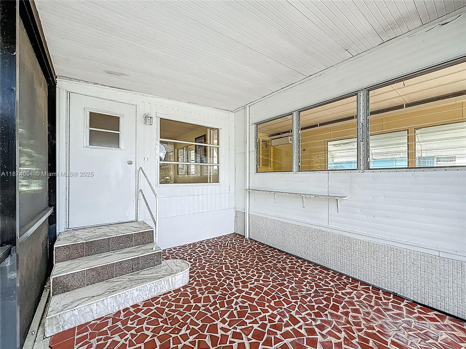 A covered porch features a red mosaic tile floor, white siding, and marble-tiled steps — 4165 S 88th Ct S, Boynton Beach FL 33436, BOYNTON BEACH, FL