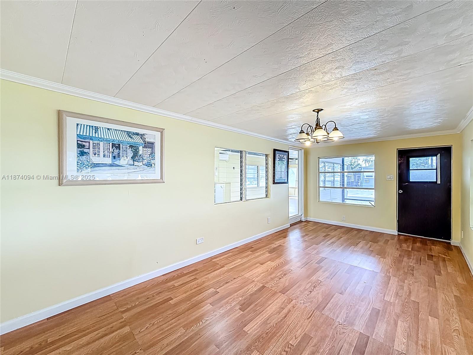 An empty room with yellow walls, wood-look flooring, a ceiling light fixture, and a door — 4165 S 88th Ct S, Boynton Beach FL 33436, BOYNTON BEACH, FL