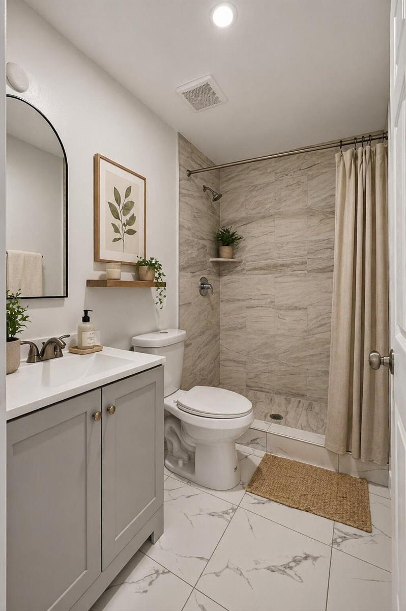 A bathroom features a gray vanity, a toilet, and a tiled shower with a beige curtain — 3255 Avenue J, West Palm Beach FL 33404, WEST PALM BEACH, FL