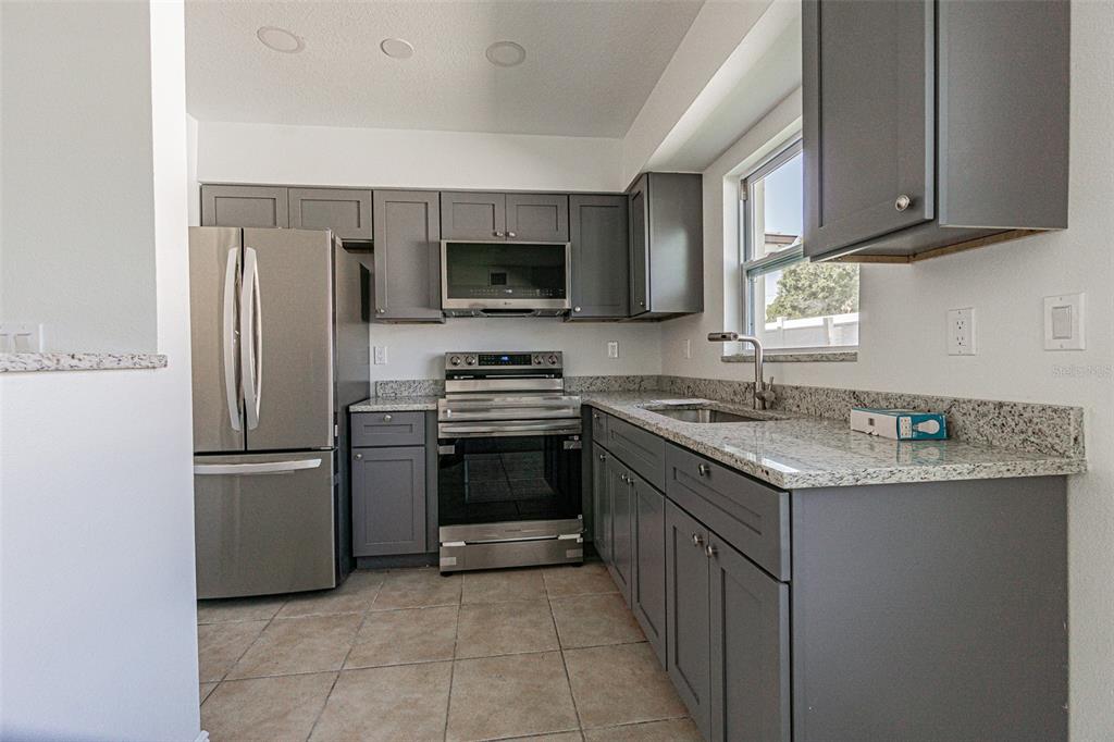 A kitchen with gray cabinets, stainless steel appliances, and granite countertops — 558 CLEARWATER LARGO ROAD N UNIT 1, LARGO, FL