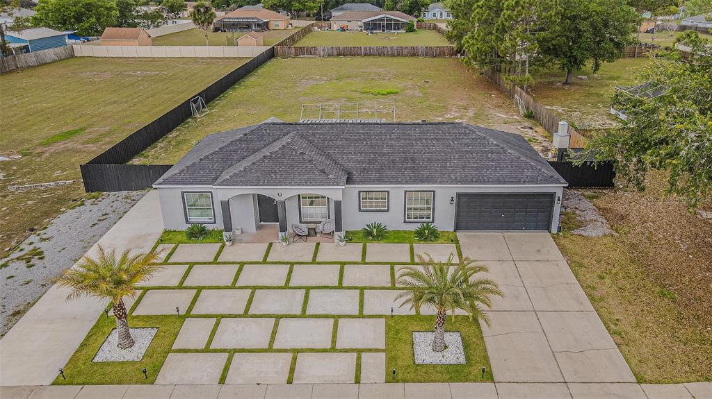 An aerial view shows a single-story house with a gray exterior, dark roof, and paved driveway — 12121 COLONIAL ESTATES LANE, RIVERVIEW, FL
