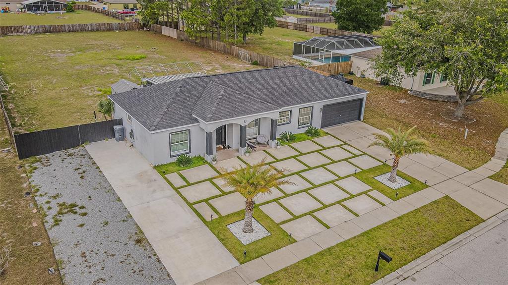 An aerial view shows a gray house with a grid-patterned concrete driveway and two palm trees — 12121 COLONIAL ESTATES LANE, RIVERVIEW, FL