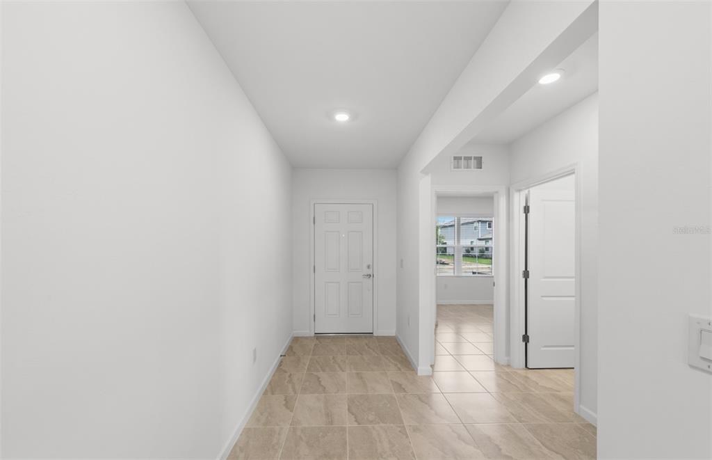 A bright entryway features light-colored tile flooring, white walls, and a white front door — 10779 SUN DROP STREET, VENICE, FL