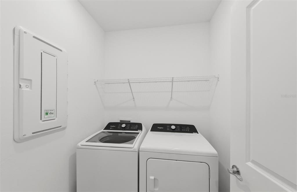 A laundry room features a white washer and dryer, a wire shelf, and a wall panel — 10779 SUN DROP STREET, VENICE, FL