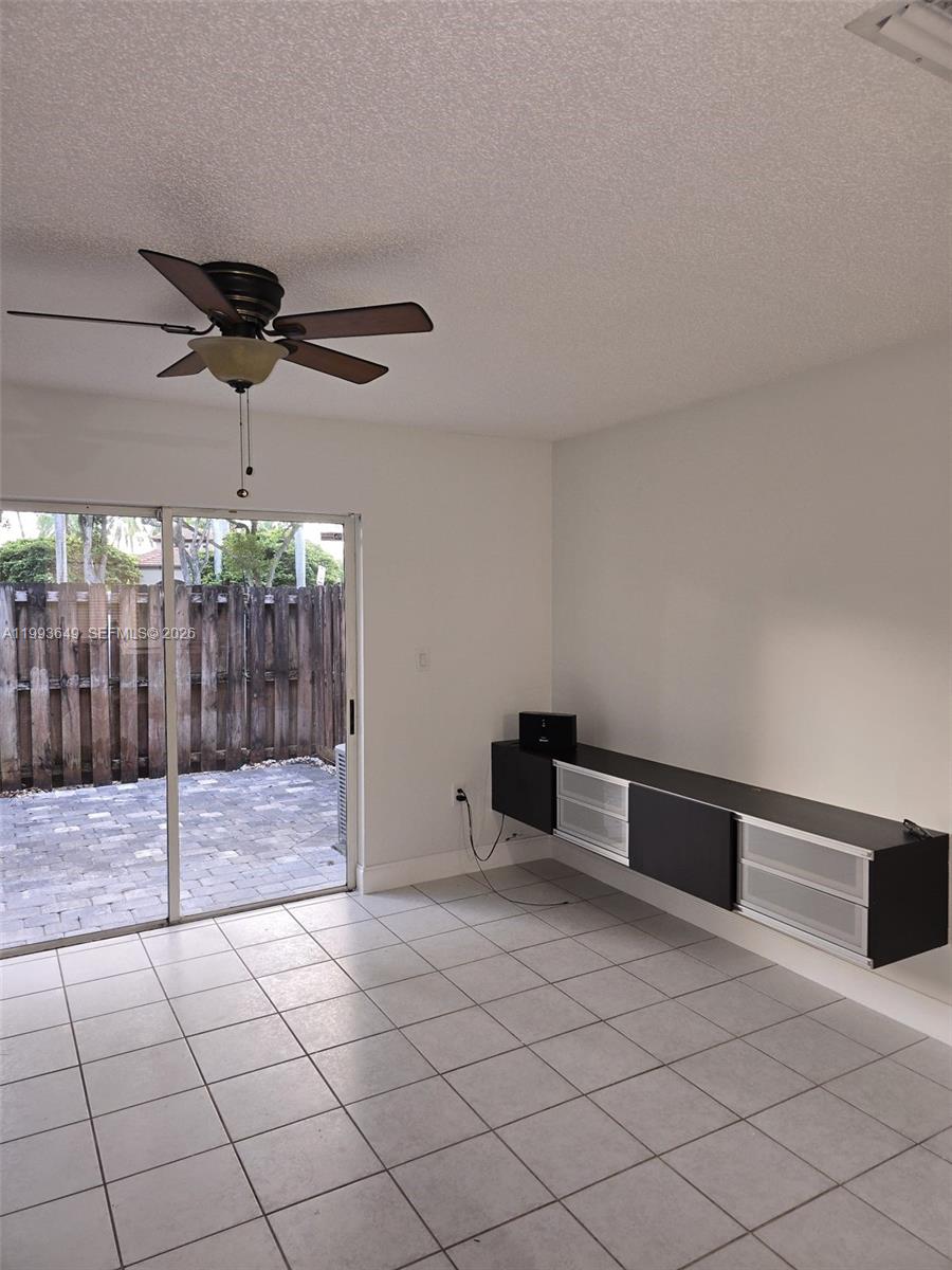 A room with white walls, tile flooring, a ceiling fan, and a wall-mounted media console — 14272 SW 121st Pl # 9, Miami FL 33186, MIAMI, FL