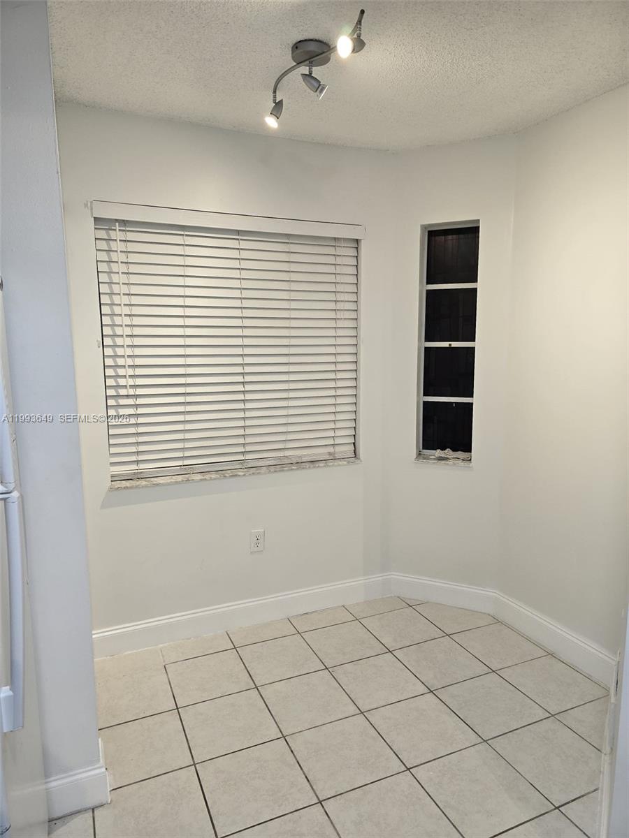 A small, tiled breakfast nook features a large window with blinds and a ceiling light — 14272 SW 121st Pl # 9, Miami FL 33186, MIAMI, FL