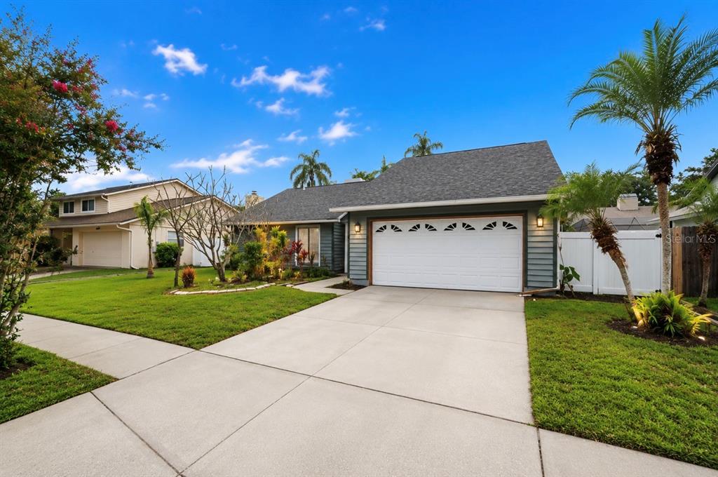 A single-story house with gray siding, a two-car garage, and a concrete driveway — 10906 AUTUMN OAK PLACE, TAMPA, FL