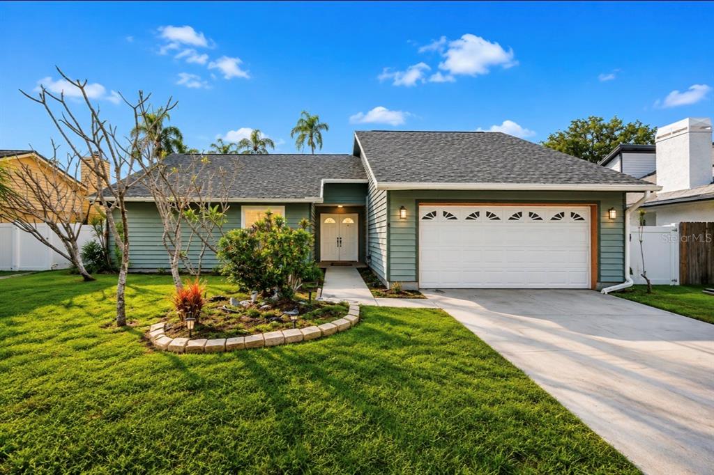 A single-story house with light green siding, a white garage door, and a landscaped yard — 10906 AUTUMN OAK PLACE, TAMPA, FL