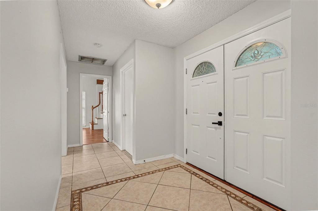 A tiled entryway features a double front door with decorative glass panels and a hallway — 10906 AUTUMN OAK PLACE, TAMPA, FL