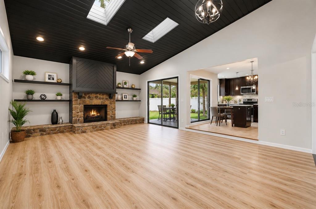 A living room features a stone fireplace, black ceiling, skylights, and wood-look flooring — 10906 AUTUMN OAK PLACE, TAMPA, FL