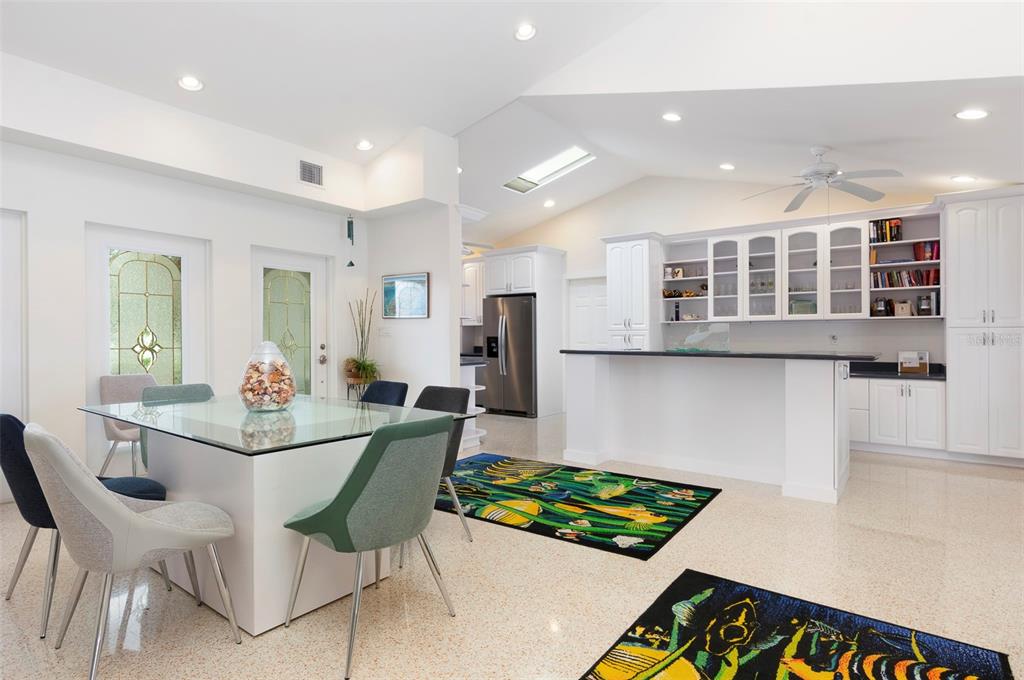 A bright kitchen and dining area with white cabinets, a glass table, and patterned rugs — 11855 4TH STREET E, TREASURE ISLAND, FL