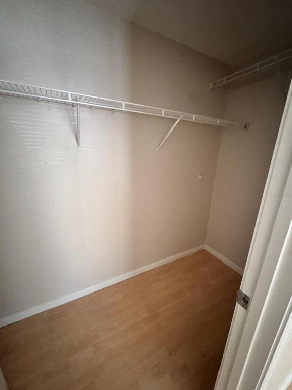 A walk-in closet with light wood flooring, beige walls, and white wire shelving — 12024 VILLANOVA DRIVE UNIT 105, ORLANDO, FL