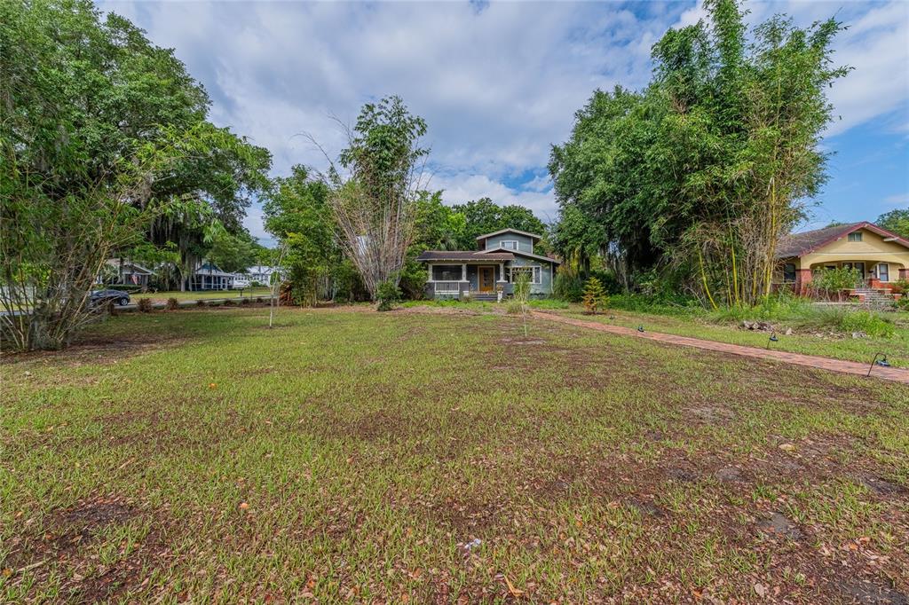 A two-story house with a front porch sits behind a large, grassy yard with trees — 116 S LAKESHORE BOULEVARD, LAKE WALES, FL
