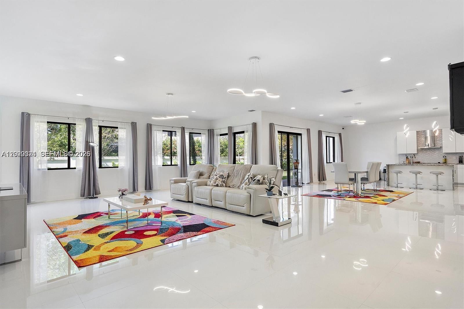 A spacious, open-concept living and dining area features white tile floors and colorful area rugs — 4406 SW 178th Ave, Miramar FL 33029, MIRAMAR, FL