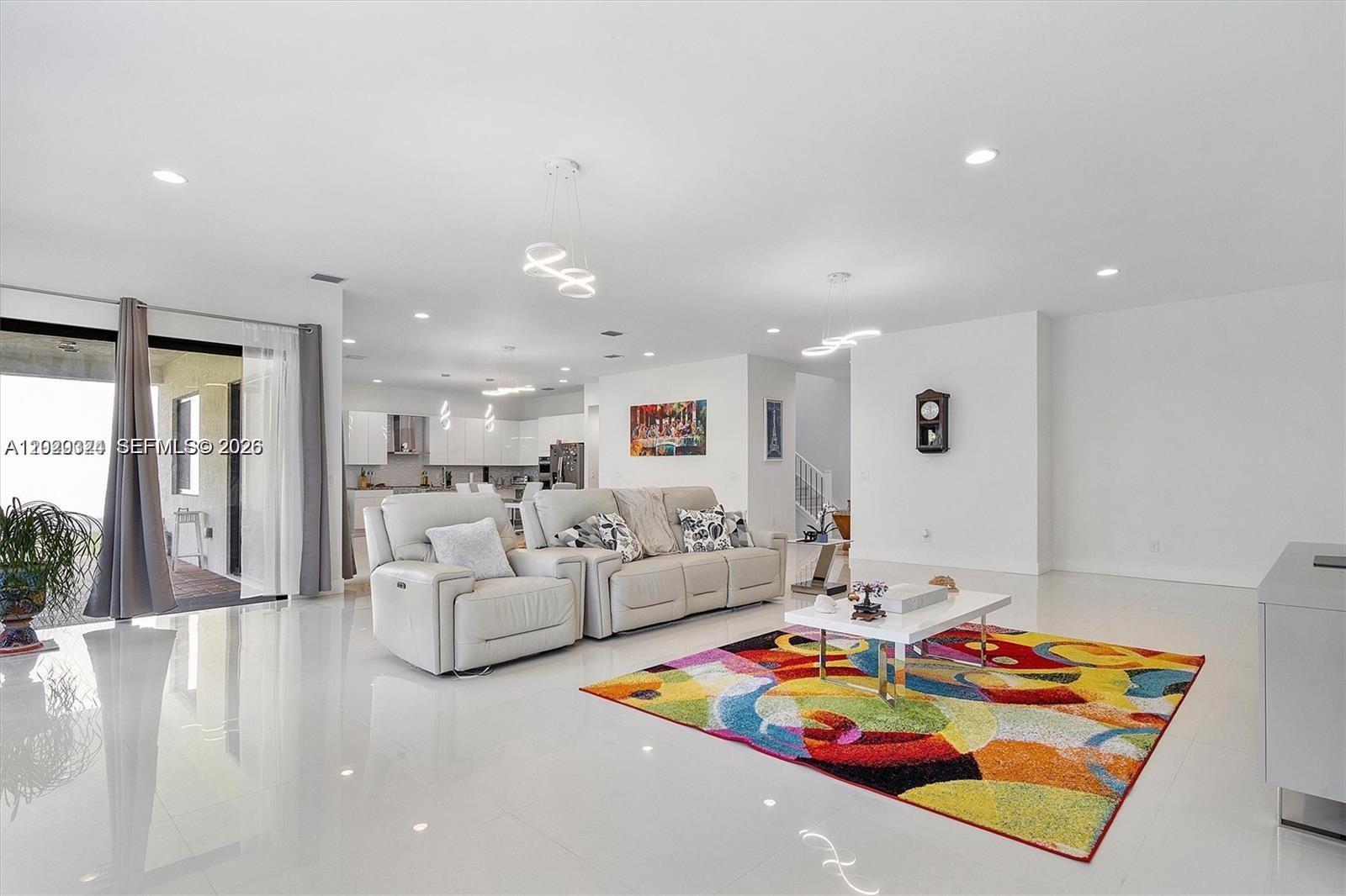 A bright, open-concept living room features white tile floors, a colorful rug, and modern lighting — 4406 SW 178th Ave, Miramar FL 33029, MIRAMAR, FL