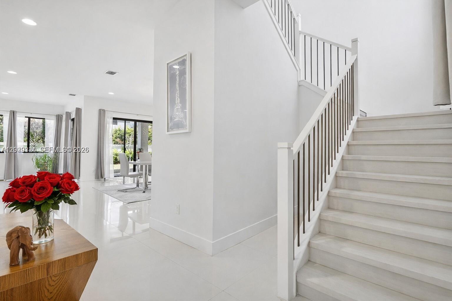 A bright entryway features a white staircase with dark railings and a vase of roses — 4406 SW 178th Ave, Miramar FL 33029, MIRAMAR, FL