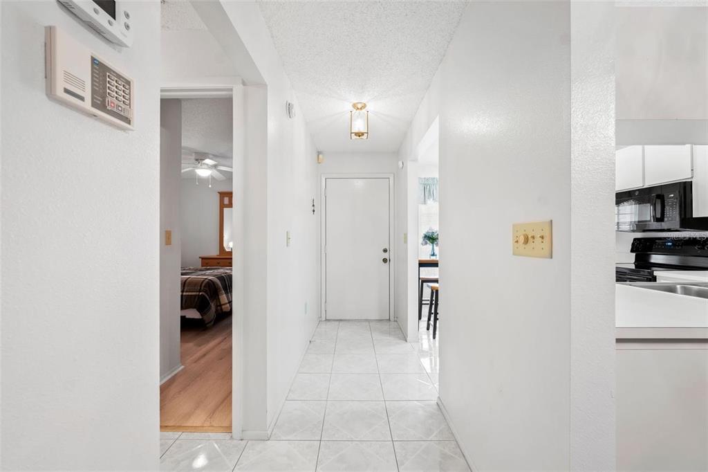 A hallway with white walls and tiled floors leads to a front door — 4557 GLEN HOLLOW, NEW PORT RICHEY, FL