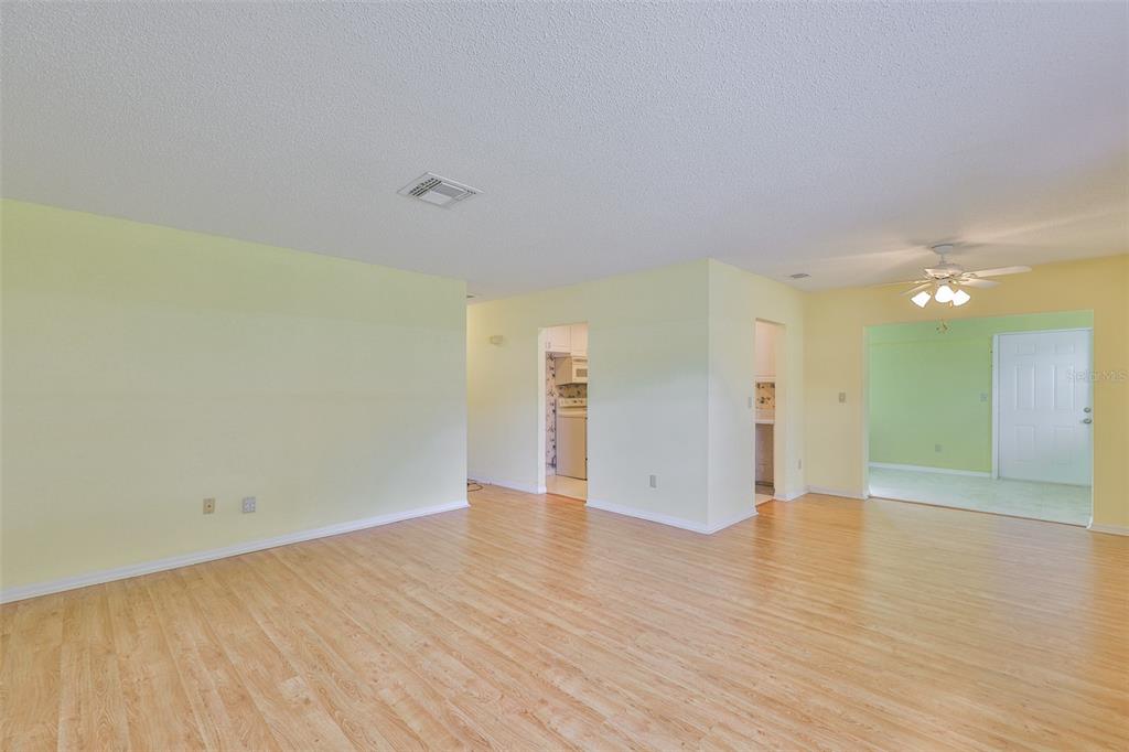 An interior view of a living area with light yellow walls and wood-look flooring — 1908 CANTERBURY LANE UNIT 20, SUN CITY CENTER, FL