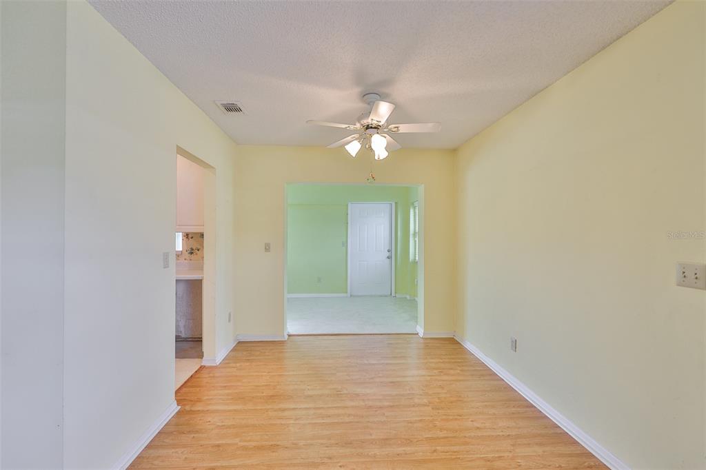 A dining area with light yellow walls, wood-look flooring, and a ceiling fan — 1908 CANTERBURY LANE UNIT 20, SUN CITY CENTER, FL