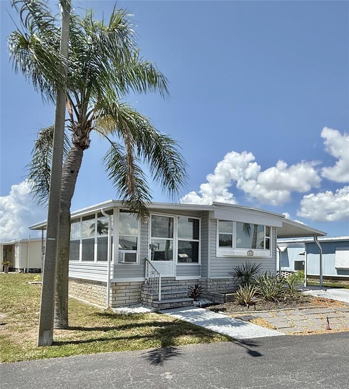 A light gray mobile home with a palm tree, stone skirting, and a carport — 614 MOUNT KEY AVENUE NE UNIT 631, ST PETERSBURG, FL