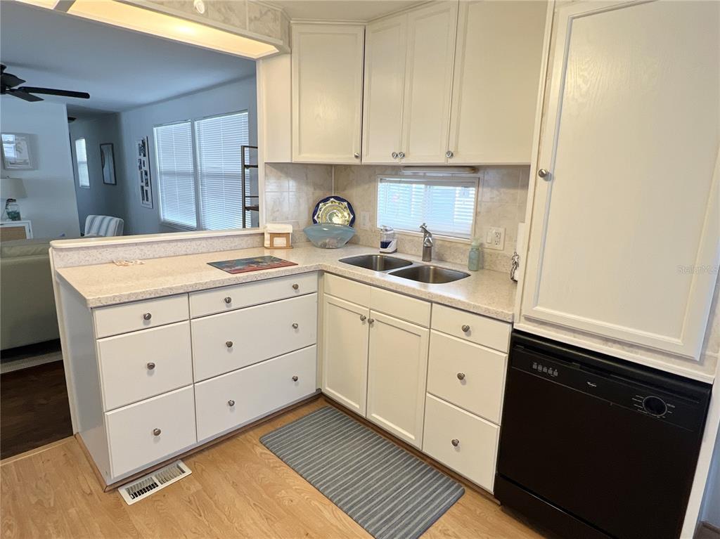 A kitchen features white cabinets, a double sink, a black dishwasher, and laminate countertops — 614 MOUNT KEY AVENUE NE UNIT 631, ST PETERSBURG, FL