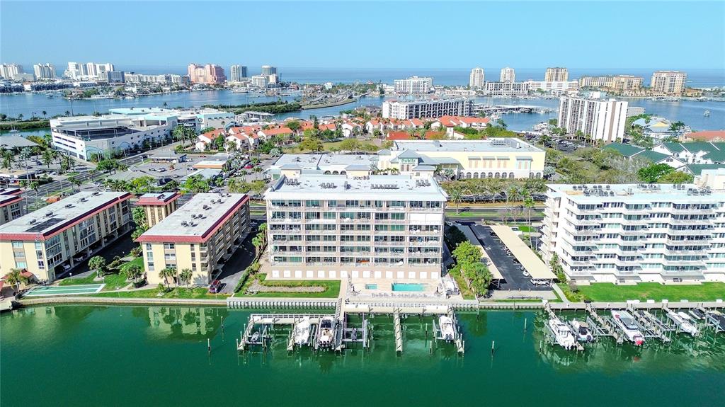 An aerial view shows a waterfront apartment complex with a pool and private boat docks — 125 ISLAND WAY UNIT 503, CLEARWATER BEACH, FL