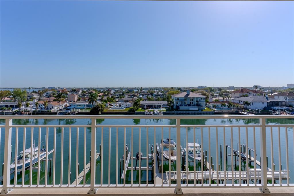 A balcony view overlooking a canal with boat slips and residential houses under a clear sky — 125 ISLAND WAY UNIT 503, CLEARWATER BEACH, FL