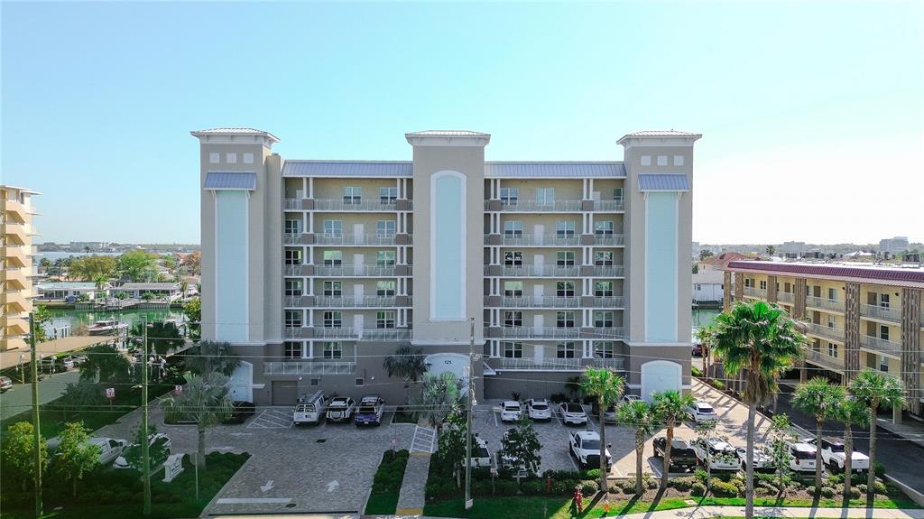An exterior view of a multi-story apartment building with a parking lot in front — 125 ISLAND WAY UNIT 503, CLEARWATER BEACH, FL