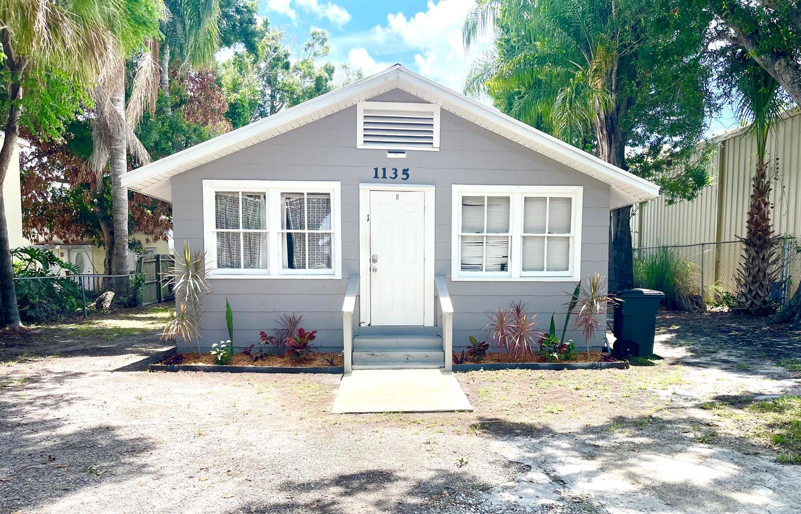 A small, gray, single-story house with a white door and a gravel front yard — 1135 17th Place, Vero Beach FL 32960, VERO BEACH, FL