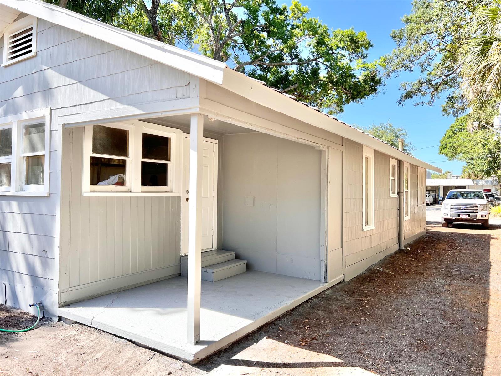 A light gray house exterior features a covered porch, white trim, and a gravel driveway — 1135 17th Place, Vero Beach FL 32960, VERO BEACH, FL