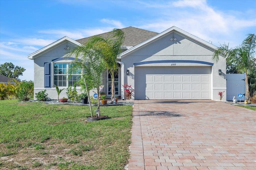 A single-story house with a light-colored stucco exterior, a two-car garage, and a paved driveway — 25157 ALCAZAR, PUNTA GORDA, FL